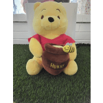 Plush Winnie the Pooh holding a honey pot with a bee
