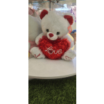 White teddy bear holding a red heart with "Love" on it