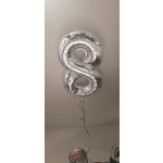 Silver foil balloons shaped like the number 8, floating indoors.