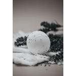 White spherical candle with dark specks on a soft surface