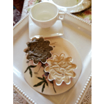 Two flower-shaped condiment cups on a tray with a white cup and saucer