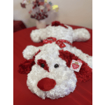 Two plush dog toys with red and white fur on a red surface
