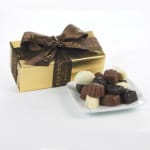Box of assorted chocolates with a ribbon bow beside a plate of chocolates