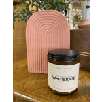 White sage soy candle in a glass jar beside a pink arched decor piece