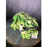 Green and black plush frog toy sitting on a patterned table