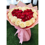 Heart-shaped bouquet of red and white roses wrapped in pink paper