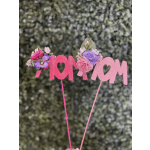 Pink glitter "MOM" sign with small floral accents on sticks