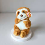 Plush sloth toy sitting on a white round base