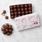 Box of chocolate-covered candies with a few pieces on a plate