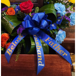Floral casket spray with roses, carnations, and blue ribbon