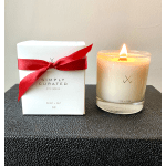 A lit candle beside a white gift box tied with a red ribbon.