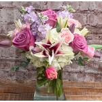 Bouquet of pink and lavender roses with white lilies in a glass vase