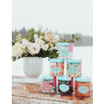 Blush and white rose arrangement in a white vase beside stacked jars of colorful candy on a snowy wooden table