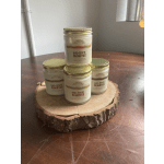 Four soy wax candles in glass jars stacked on a wood slice