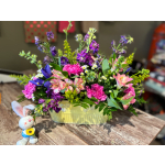 Mixed bouquet in a pale yellow basket with a small bunny figurine beside it