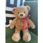 Plush teddy bear with a red ribbon sitting on a green chair