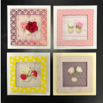 Four framed paper flower mini arrangements in pink, red, yellow, and lavender.
