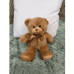 Brown teddy bear with a ribbon sitting on a shaggy rug