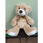 Plush teddy bear with a gold ribbon sitting on a small stand