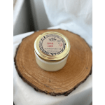 A jar candle with a gold lid sits on a wood slice