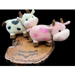 Three plush cows with heart patches on a wooden slab