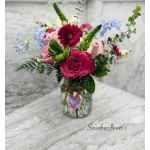 Mixed bouquet in a glass jar with pink, red, and blue flowers
