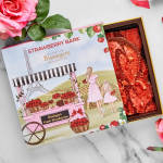 Box of strawberry bark candy beside pink roses