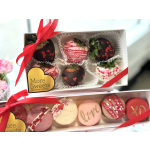 Boxes of decorated chocolate-covered strawberries and macarons tied with red ribbons