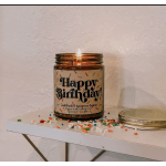 Lit birthday candle in an amber glass jar with sprinkles around it
