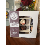 Box of assorted chocolates with a floral arrangement in the background