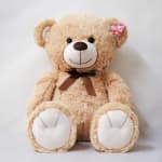 Large beige teddy bear with a brown ribbon bow