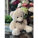 Plush teddy bear in front of a floral arrangement