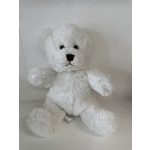 White plush teddy bear sitting against a plain wall