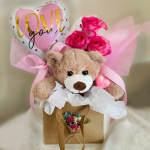 Gift bag with teddy bear, heart balloon, and hot pink roses with tissue and ribbons