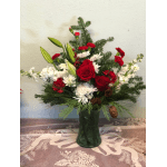 Red roses and white flowers arranged in a green glass vase with pine accents