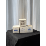 Three boxed bath bombs on a black table in front of white curtains.