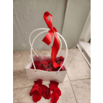 White gift bag with red rose petals and a red ribbon bow