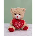 Teddy bear holding a red heart pillow