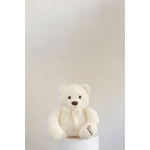 White teddy bear with a ribbon sitting on a pedestal