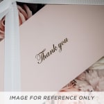 Pink gift box with a white ribbon and thank you card