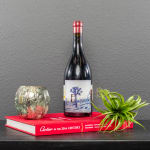 Wine bottle, small candle holder, and air plant on a red book