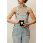Person holding a dark glass candle jar with a cork lid