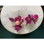 Pair of magenta orchid and peach rose boutonnieres on a round stone surface