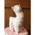 Plush white llama with pink ears and feet on a lace-covered surface