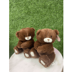 Two brown teddy bears sitting on a white surface