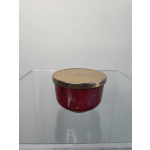 Red glass candle jar with a gold lid on a clear surface