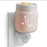 Pink plug-in wax warmer with a white wall outlet base