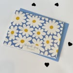 Blue floral paper goods package with white daisies and yellow centers
