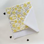 Decorative floral greeting card with yellow blossoms and white envelope