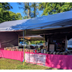 Outdoor market stall selling homemade sweets in clear containers on pink-covered tables